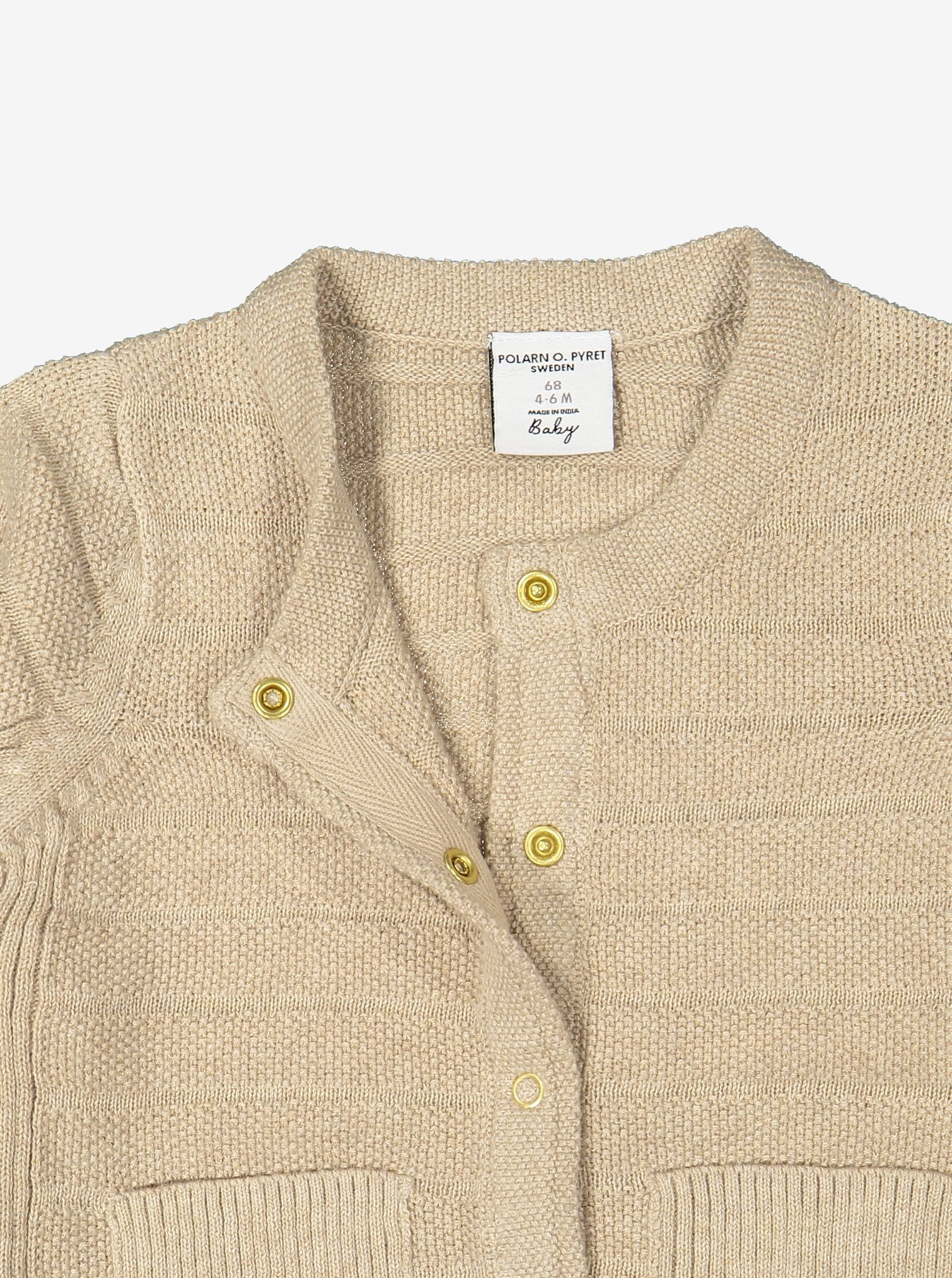 Close up of unisex beige knitted cardigan in 100% organic cotton showing easy popper fastening. 