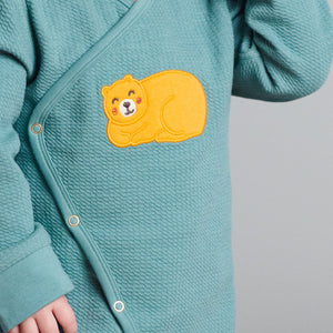 Close up toddler wearing wraparound newborn baby overall showing textured detail, popper fastening and adorable sleeping bear applique