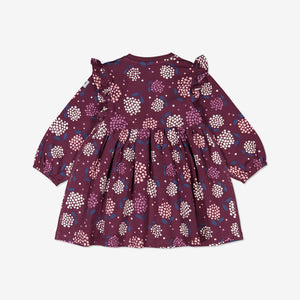 The back of a purple floral long sleeve baby dress, designed with shoulder ruffles. Made of organic cotton.