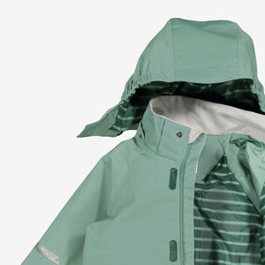 A closeup shot of a green, kids waterproof shell jacket with detachable hood, made of fabric and 100% polyester lining. 