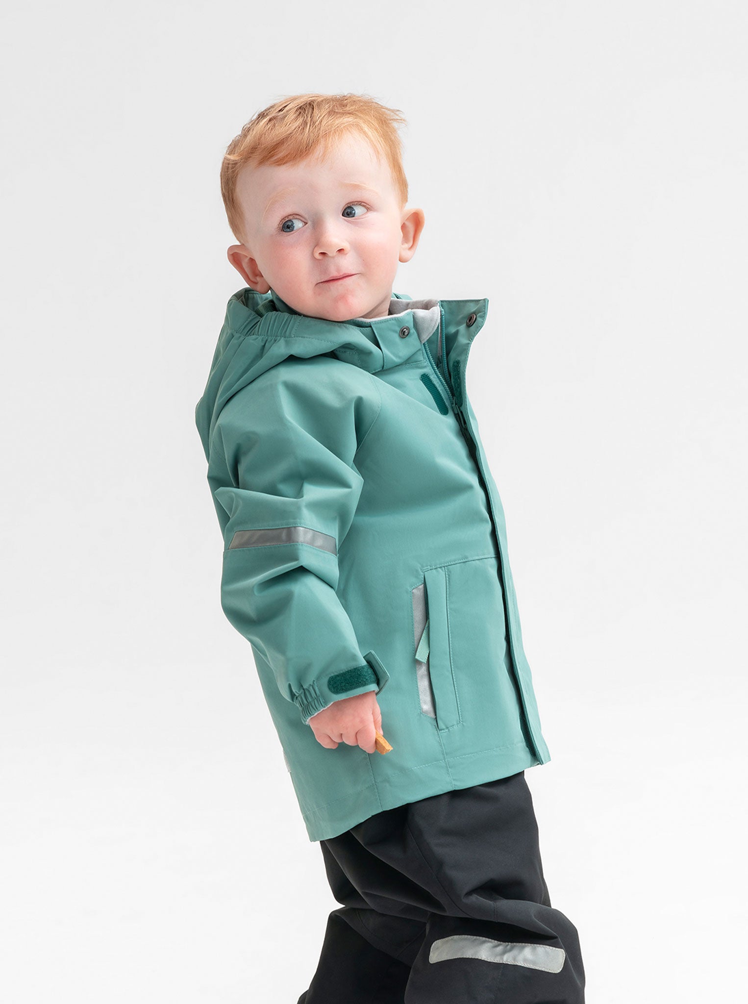 Kids waterproof shell jacket in colour green, with front pockets and detachable hood, made of lightweight and durable fabric.