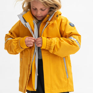 A young girl wearing a yellow, kids waterproof shell jacket paired with a yellow, kids waterproof fleece jacket.