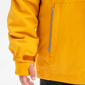 Close up shot of the pocket and adjustable cuff of a yellow, kids waterproof jacket, made of lightweight shell fabric.